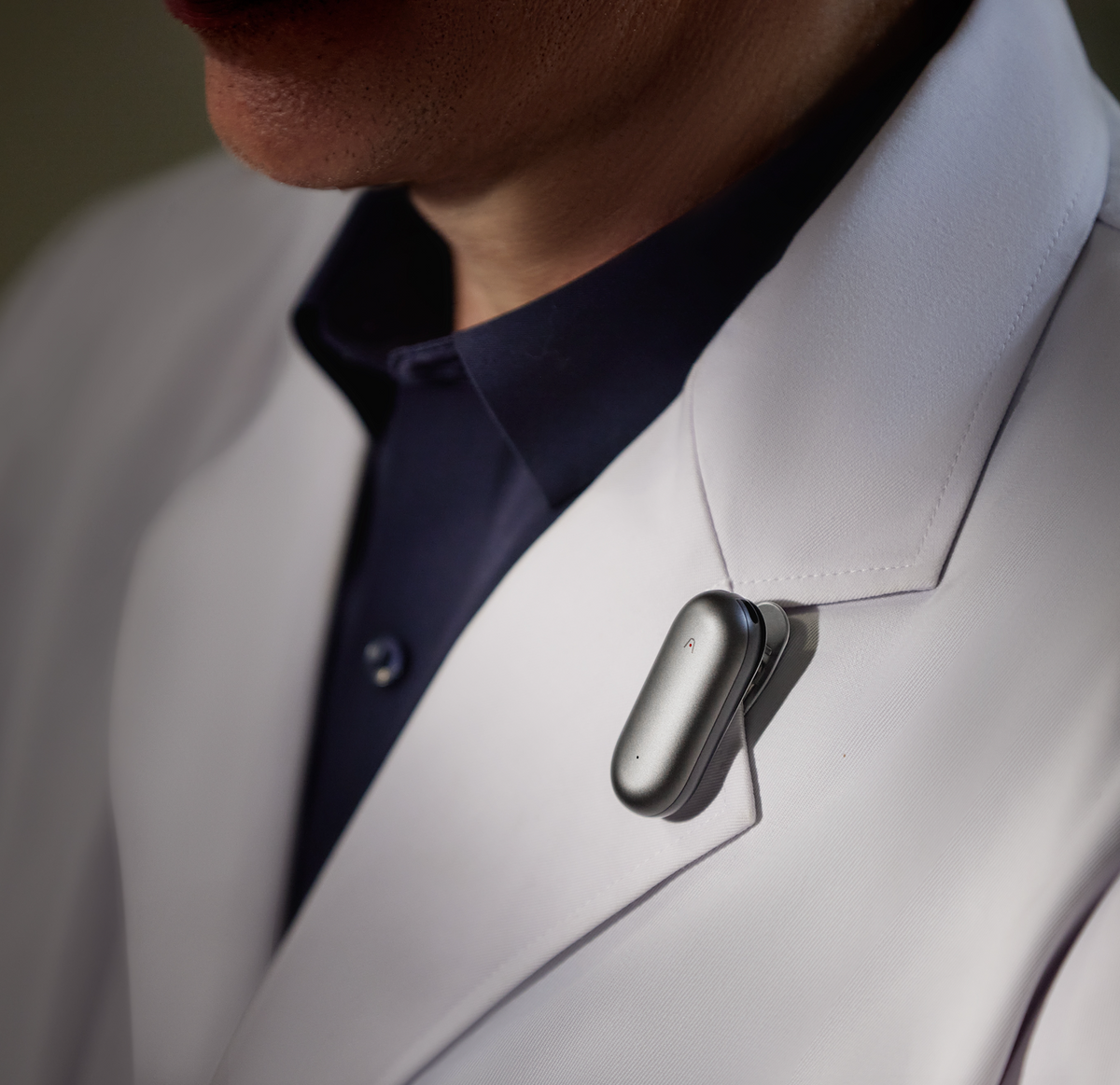 Plaud NotePin worn on a white lab coat lapel for professional AI note-taking.