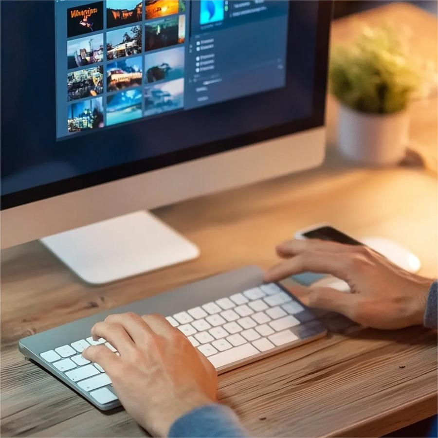 Person using a Mac computer with a keyboard and mouse, browsing a game library on the screen.