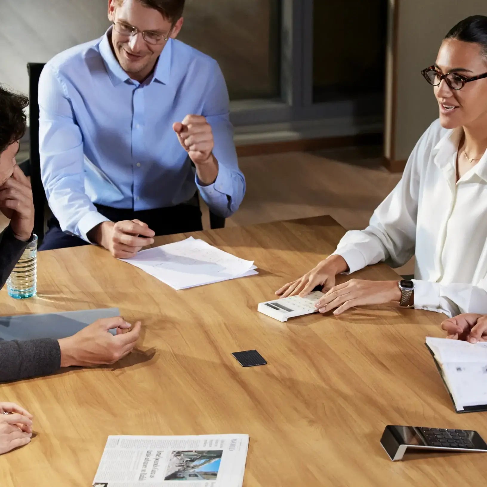 A black Plaud Note records a business meeting as professionals sit around a wooden conference table.