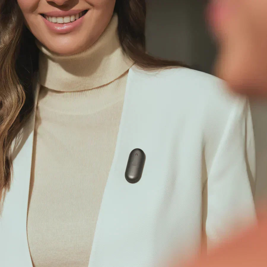 A woman wearing a black Plaud NotePin S on her white blazer lapel.