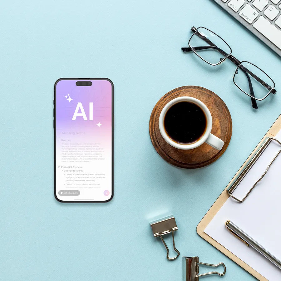 A top-down view of a light blue desk with a smartphone displaying an AI Note Taker interface, alongside coffee, glasses, and office supplies.