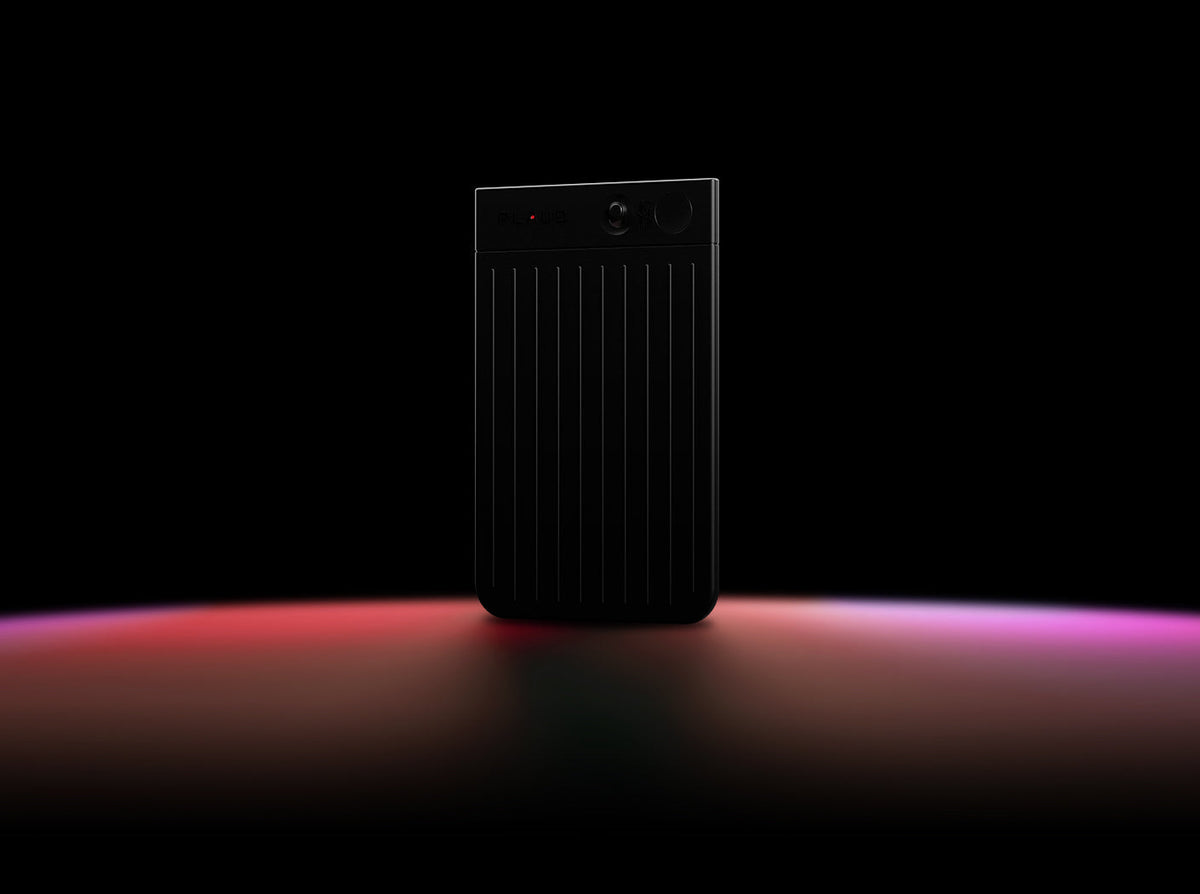 Black Plaud Note featuring a ribbed texture and display screen, illuminated by red and purple light.