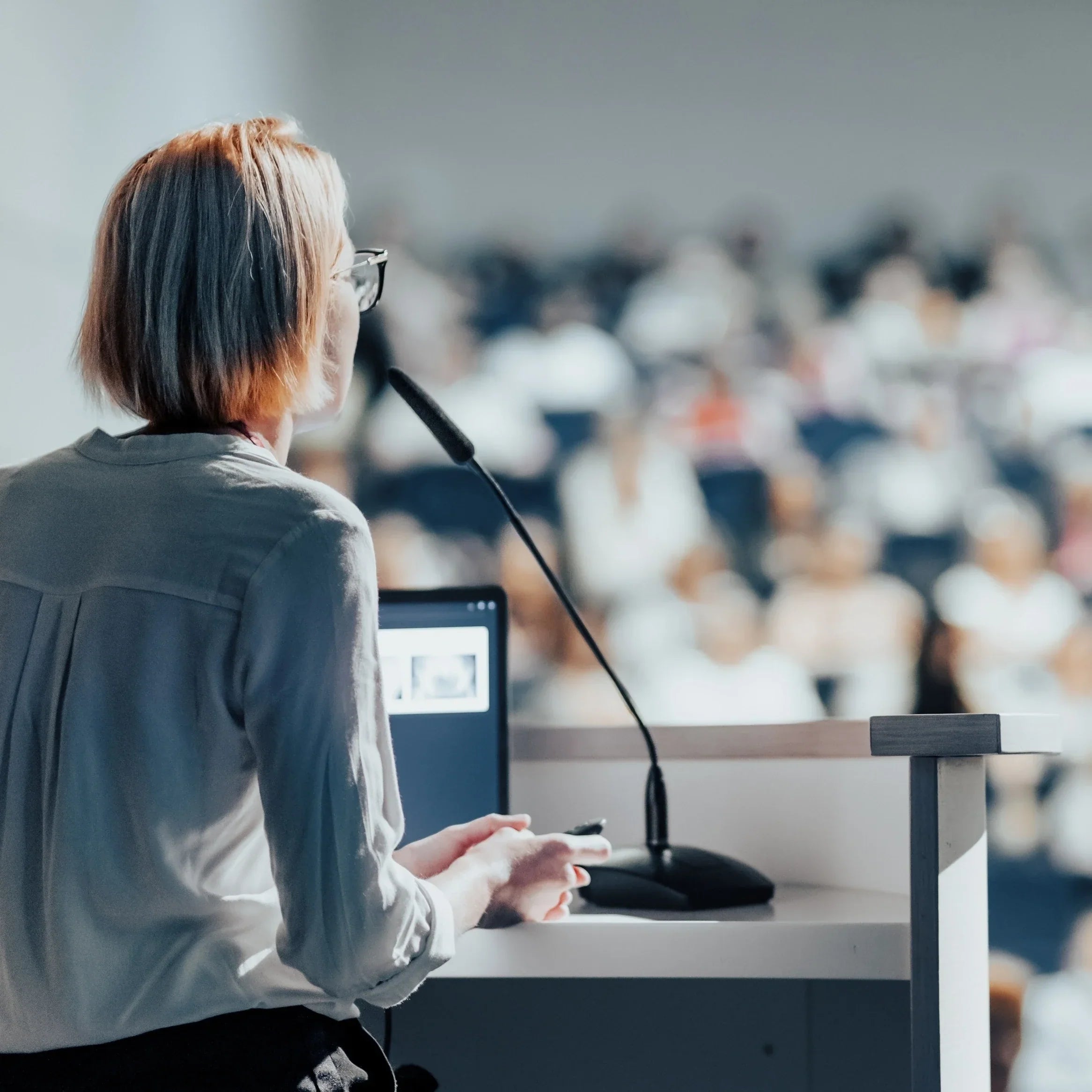 Speaker addressing a large conference audience from behind a podium.