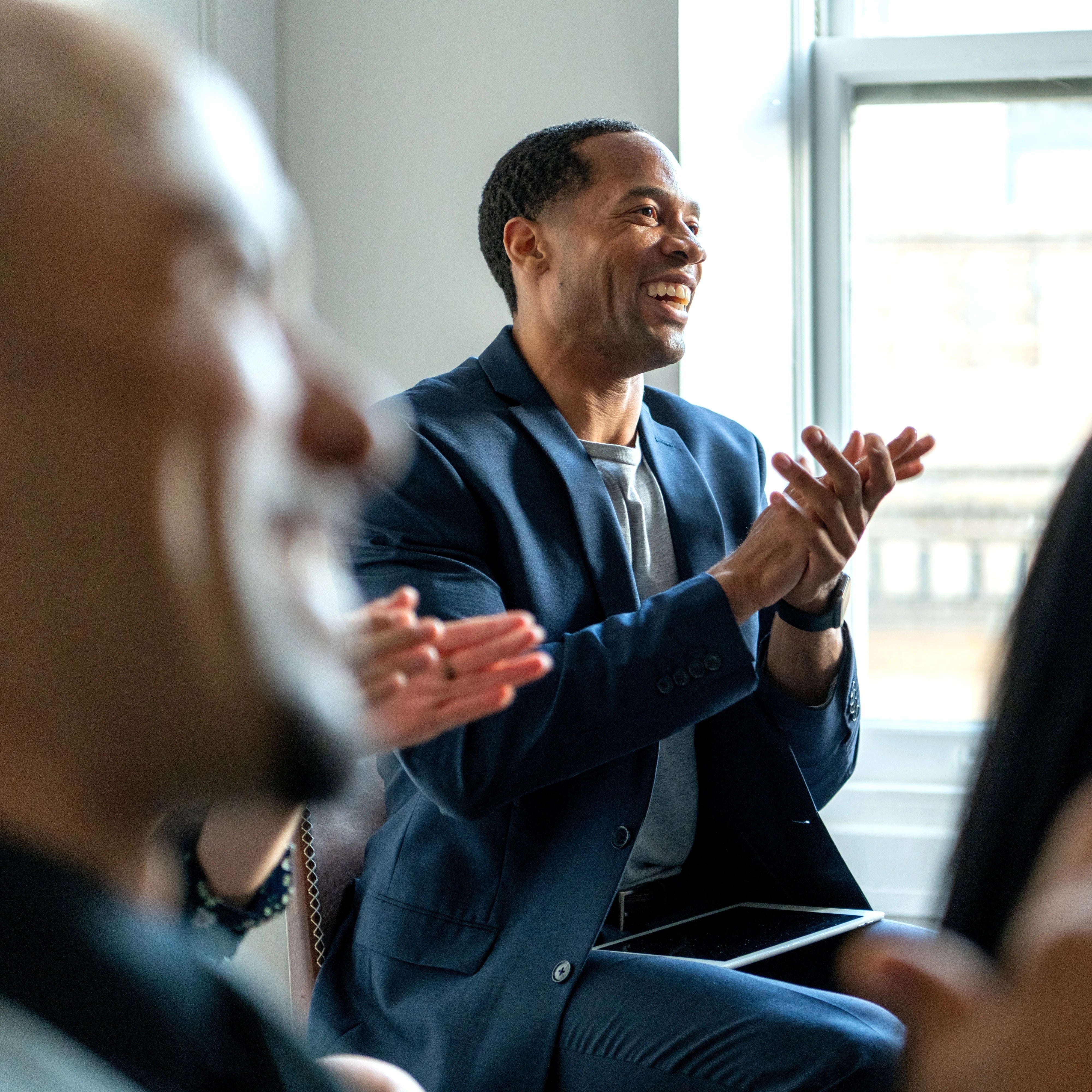 Professionals reacting and applauding during a discussion at a professional event.