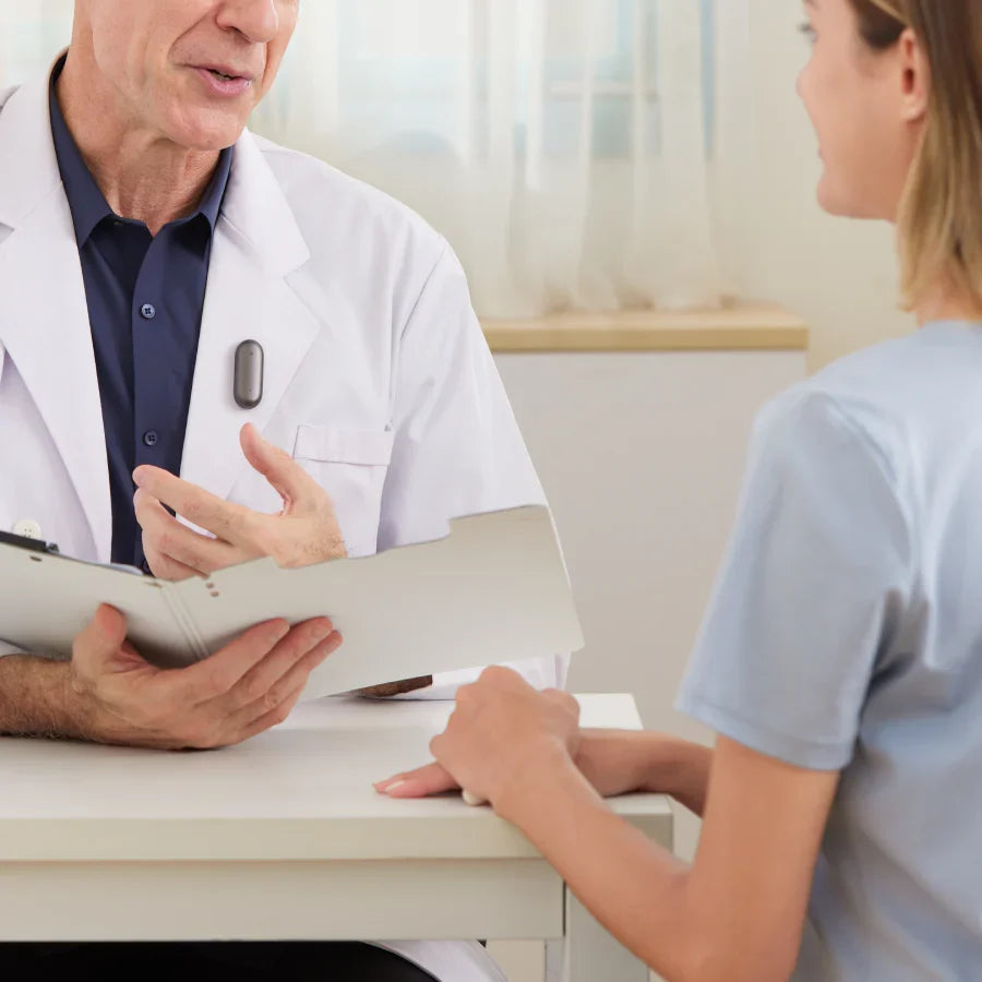 Doctor wearing a Cosmic Gray Plaud NotePin on a white coat during a patient consultation.