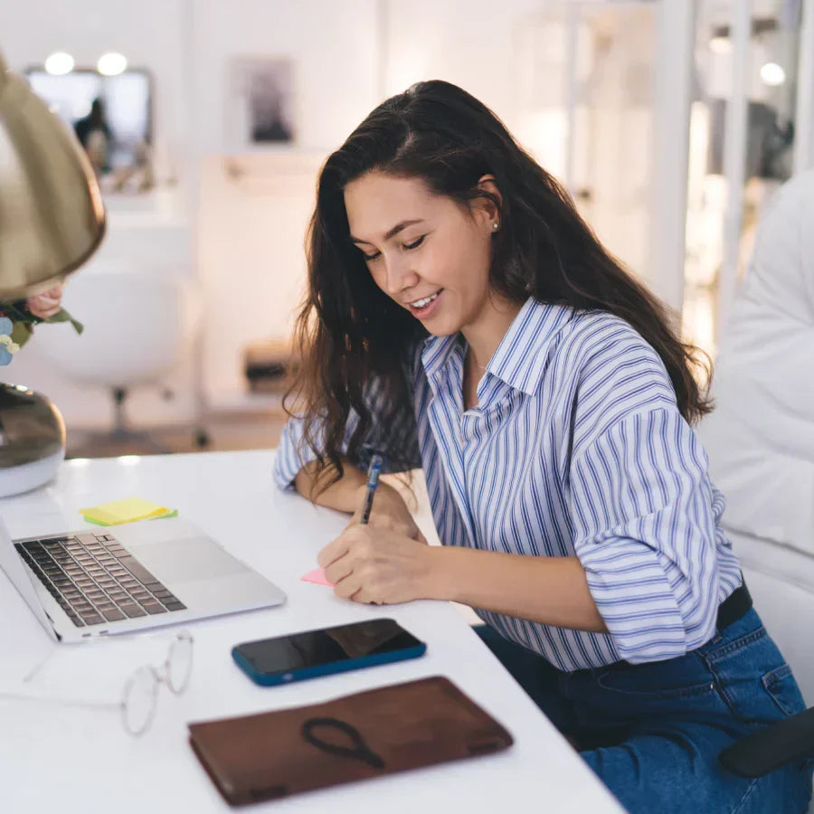 A professional woman wearing a Plaud NotePin on her teal blazer during an office meeting.