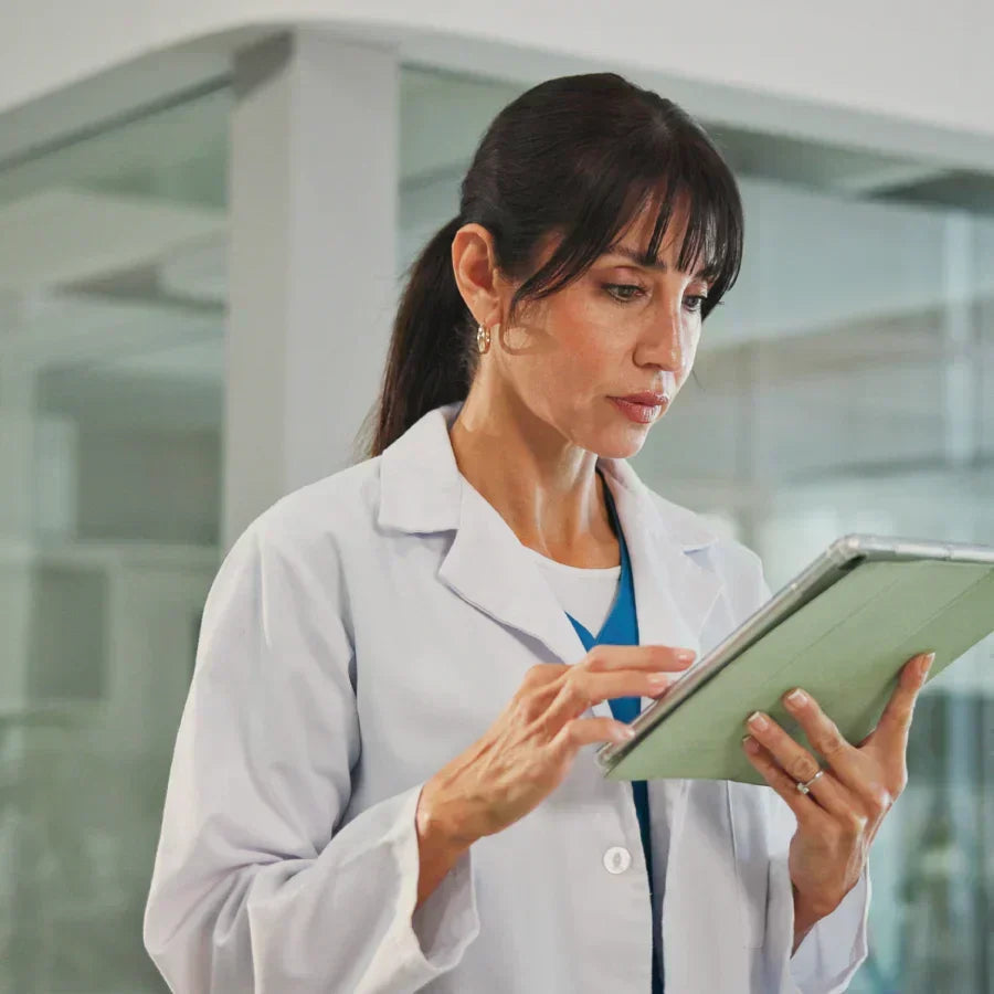 Doctor in a lab coat using a tablet while wearing a silver Plaud NotePin.