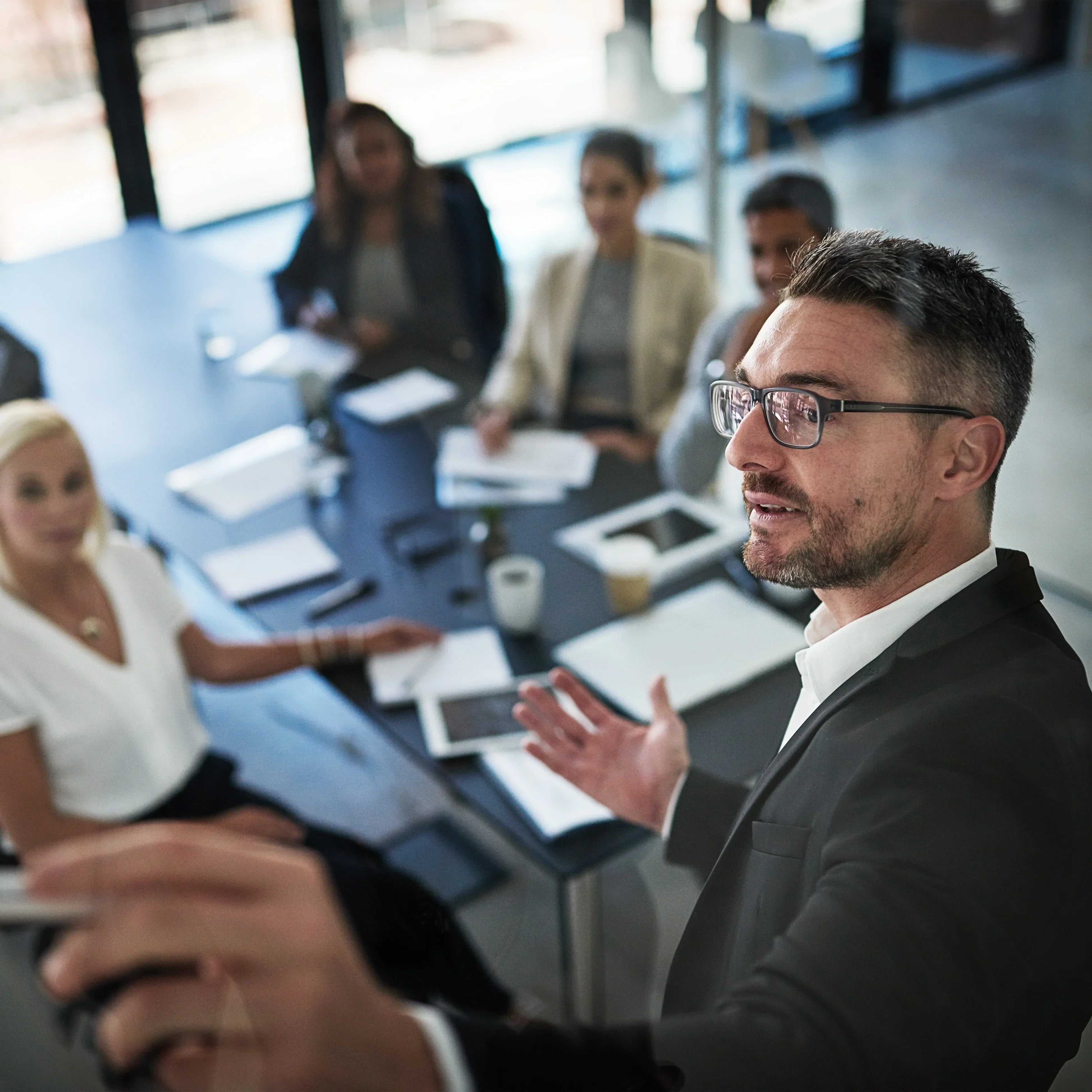 Presenter addressing colleagues around a conference table during a business meeting.