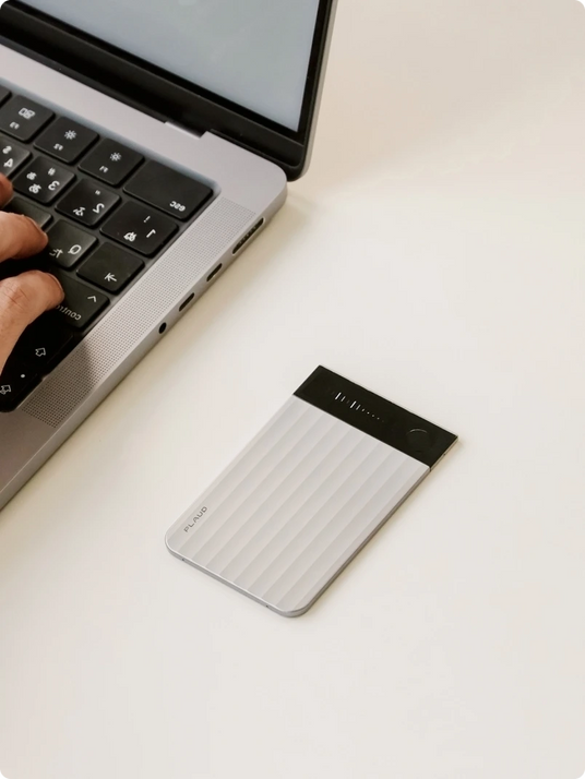 A Plaud Note Pro on a desk next to a laptop