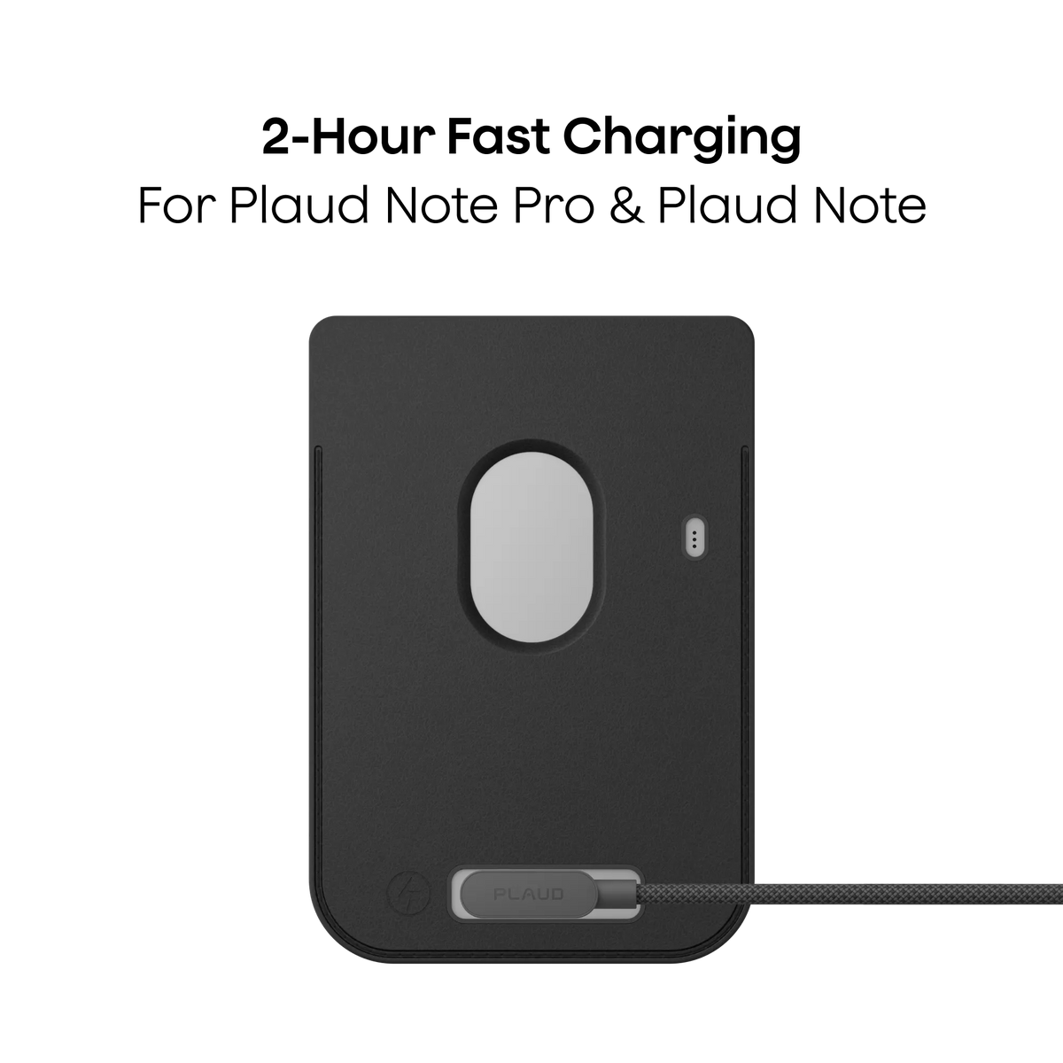A black Plaud AI voice recorder sits inside a matching black magnetic case while charging via a grey braided cable.
