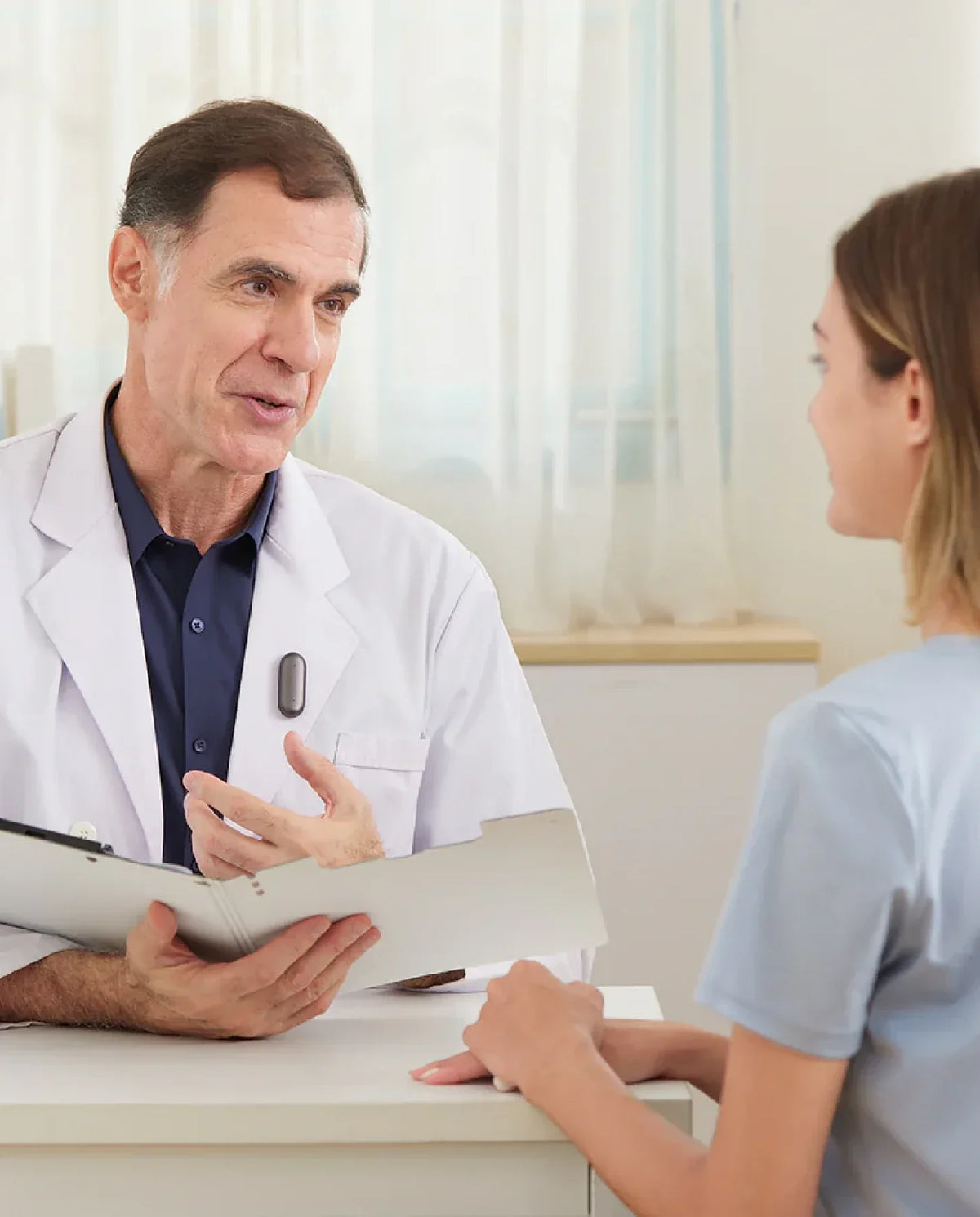 Doctor wearing a Plaud NotePin on his lab coat during a patient consultation.