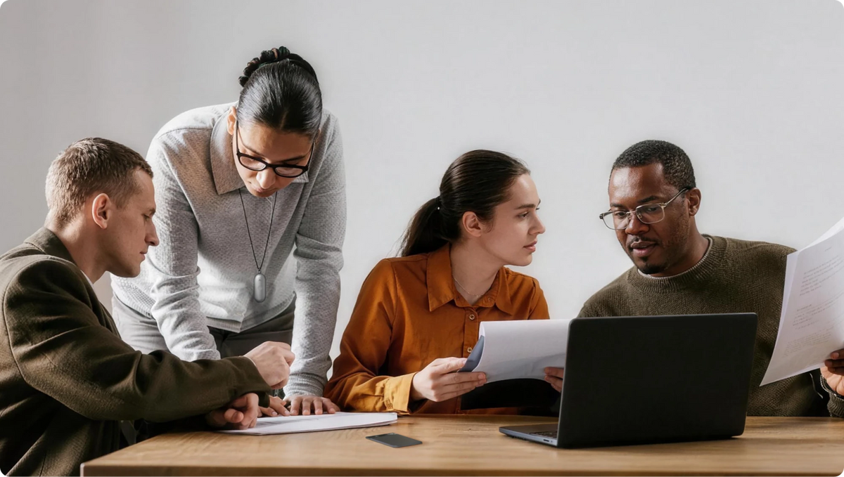 Colleagues collaborating in a meeting with a silver Plaud NotePin S wearable and a black Plaud Note on the table.